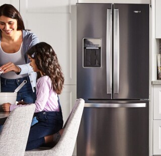 Person and child standing in front of a stainless steel refrigerator