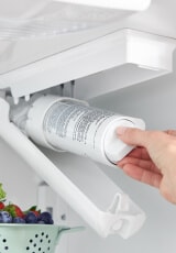 Person placing a water filter inside a refrigerator