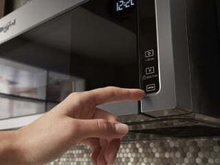 Person selecting a microwave setting on a control panel
