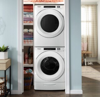 White stacked front load washer and dryer set inside a closet