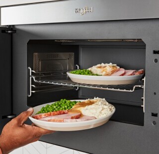 A person heating up two plates of food in a microwave