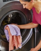 Person loading laundry into a front load washing machine