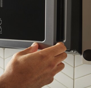 A hand opening a microwave door