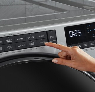 A person selecting a wash cycle on a washing machine