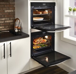 An opened double wall oven with food cooking inside