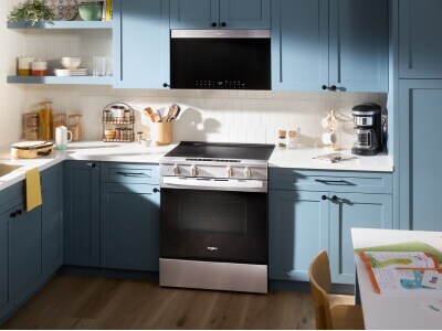 A kitchen with blue cabinetry and an induction cooktop with an over-the-range microwave above it