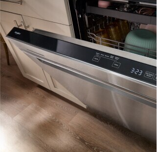 An open stainless steel Whirlpool® Dishwasher with dishes inside