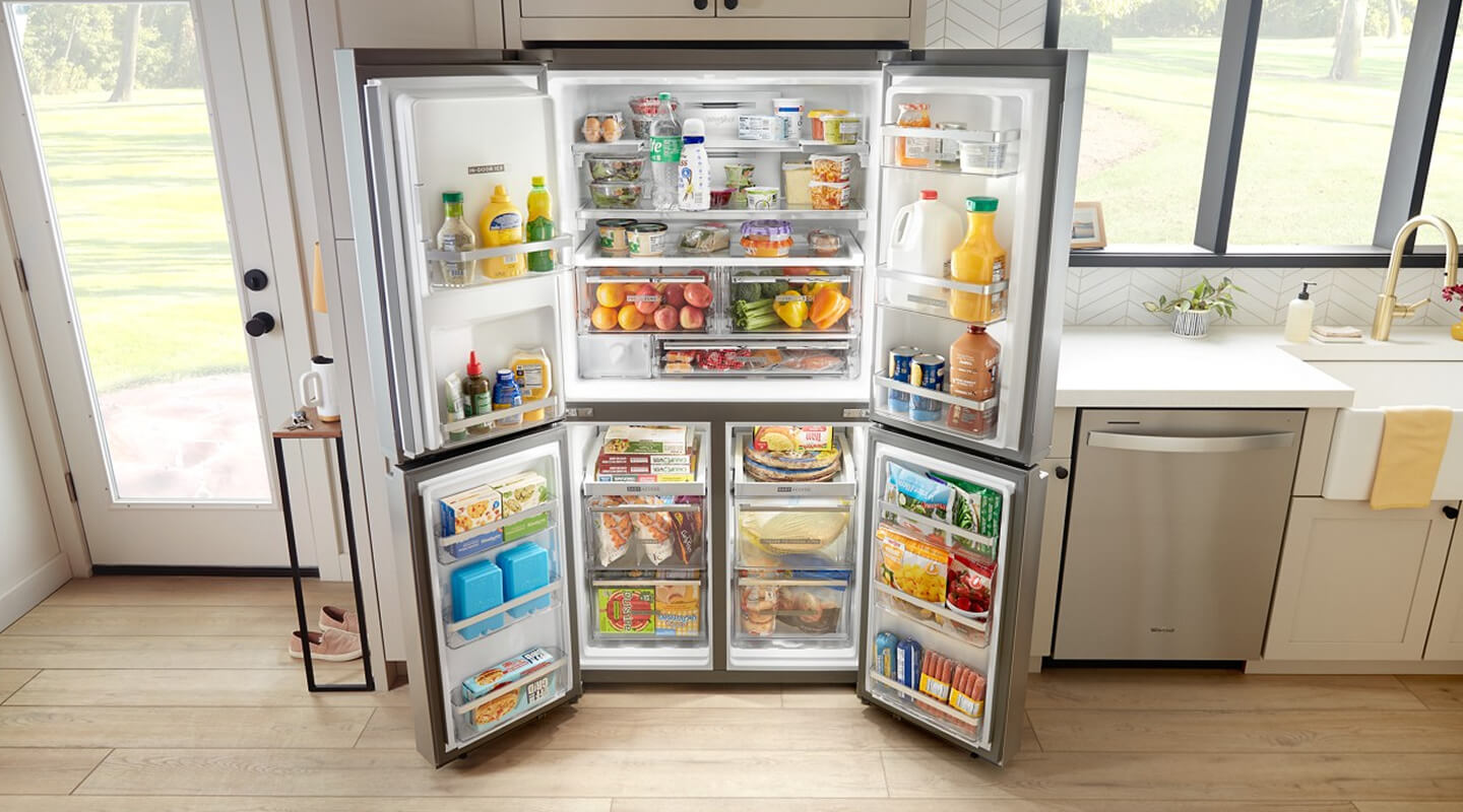 Fully stocked, open 4-door refrigerator built into tan cabinetry Fully stocked, open 4-door refrigerator built into tan cabinetry