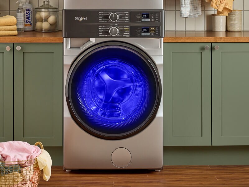 Blue UV lighting shining inside a Whirlpool® Front Load Laundry Tower washer