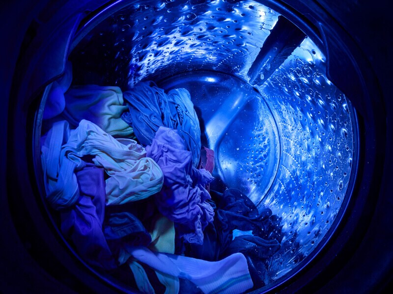 UV cleaning technology shining a blue light inside a wash basket with clothes