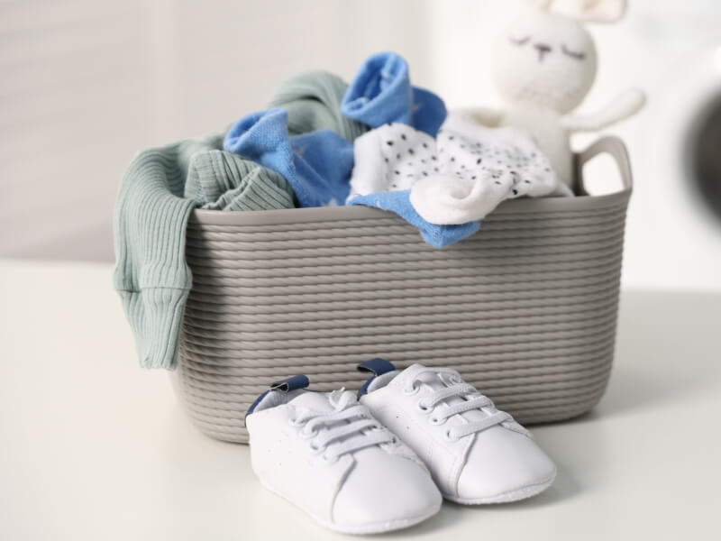 Baby clothes inside a basket with shoes in front