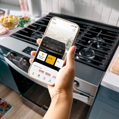 Hand holding a smartphone with oven control app open
