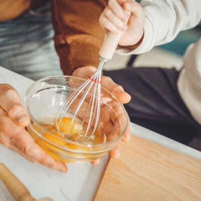 Child stirring an egg with a whisk