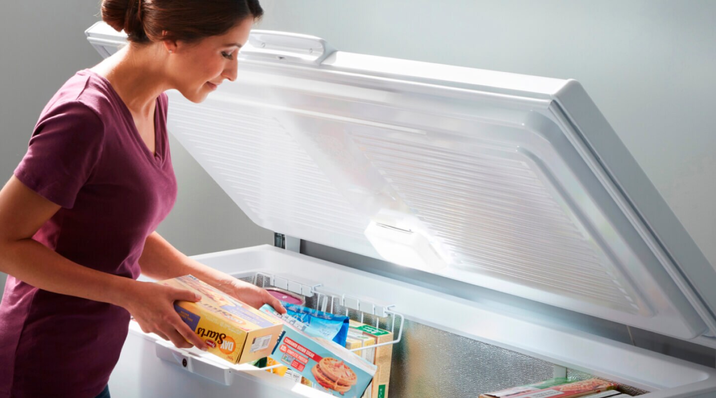 Person stocking items in a chest freezer