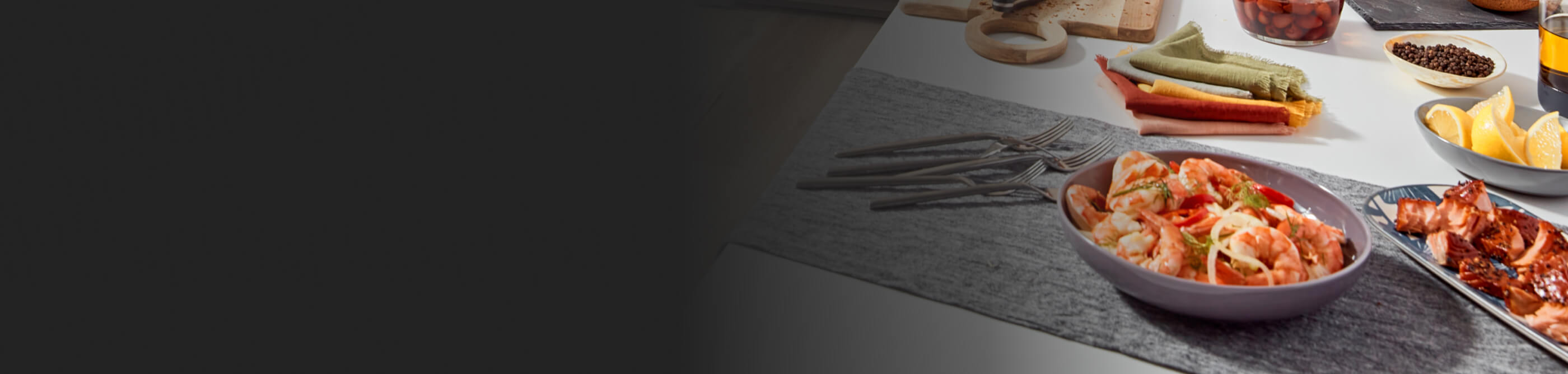 A bowl of shrimp pasta on a table with other fresh ingredients