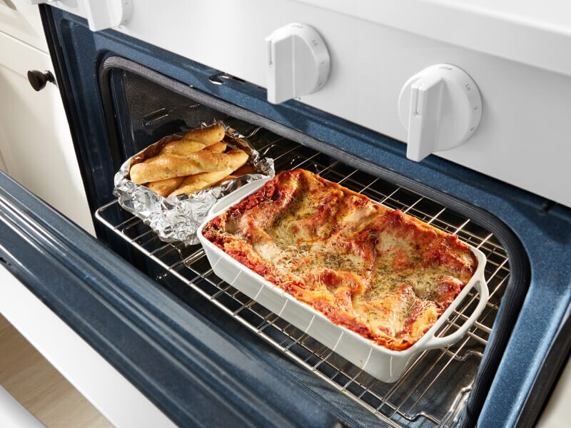 Casserole and breadsticks in an oven