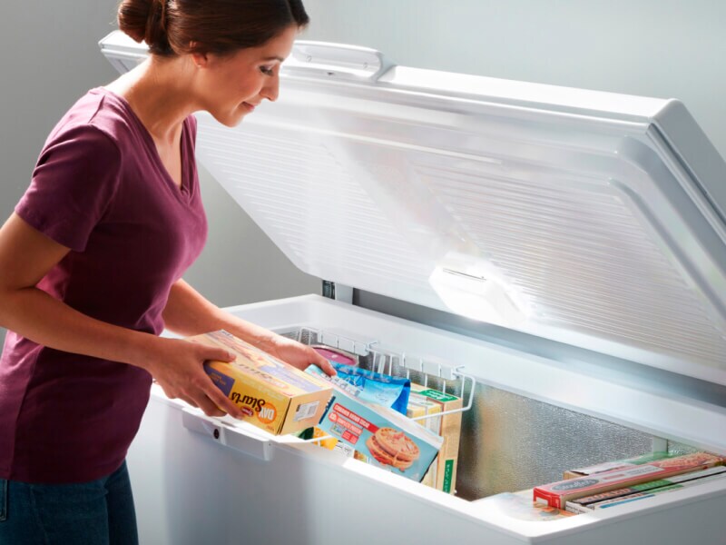 Person stocking items in a chest freezer
