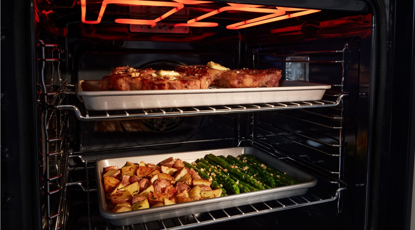 Pans of food cooking inside oven Pans of food cooking inside oven