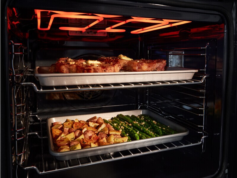 Pans of food cooking inside oven Pans of food cooking inside oven