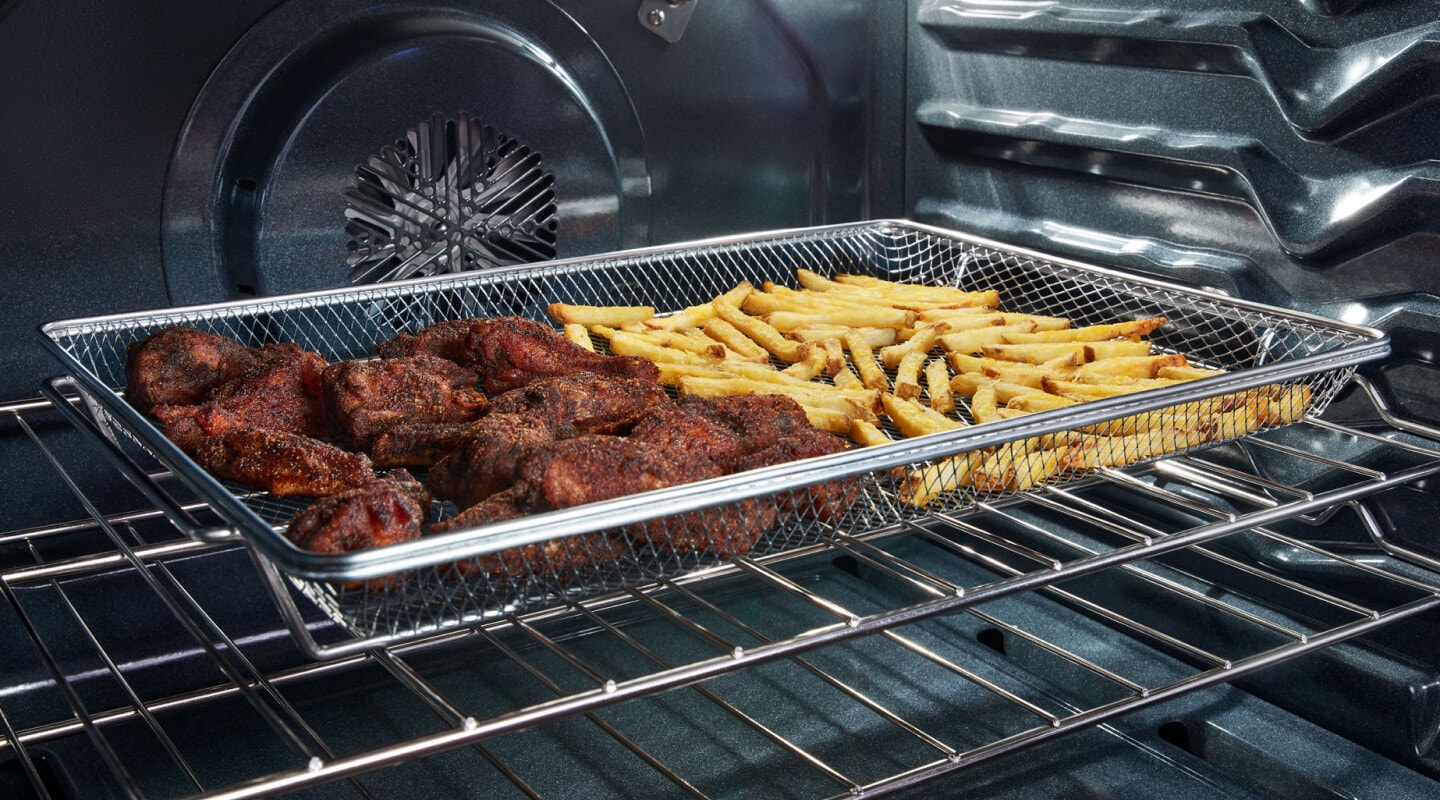 Chicken wings and fries in an air fry basket inside a Whirlpool® oven Chicken wings and fries in an air fry basket inside a Whirlpool® oven