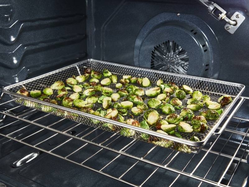 Zuccinni cooking in an air fry basket. Zuccinni cooking in an air fry basket.