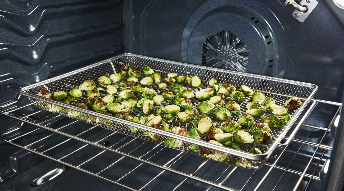 Zuccinni cooking in an air fry basket. Zuccinni cooking in an air fry basket.
