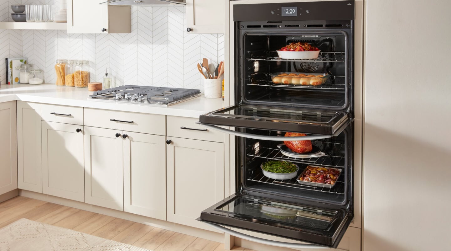 Dishes cooking in an open double oven in a modern kitchen