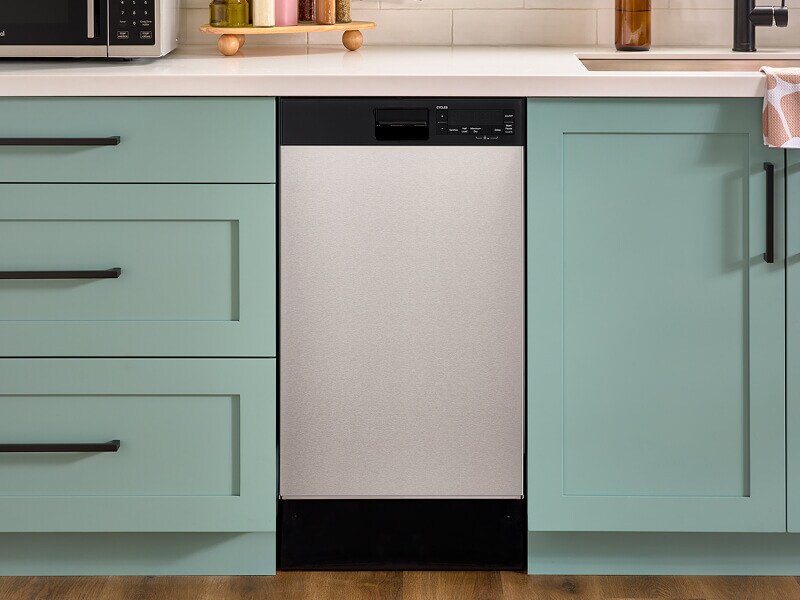 An 18" Whirlpool® Dishwasher set in mint green cabinetry
