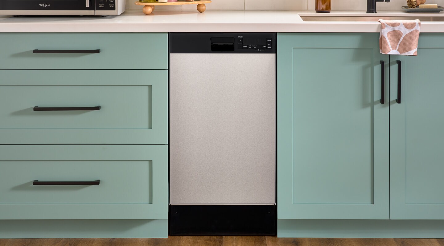 An 18" Whirlpool® Dishwasher set in mint green cabinetry