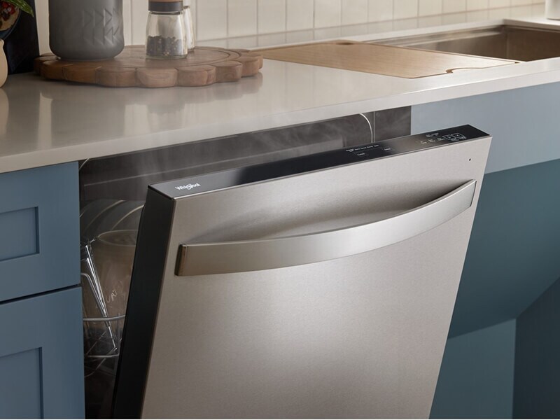 An open Whirlpool® Dishwasher with steam coming out