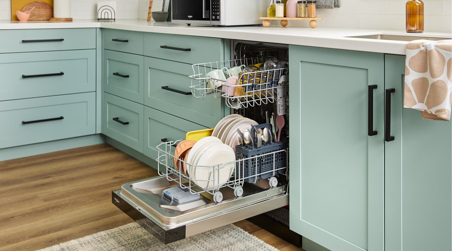 An open Whirlpool® Dishwasher surrounded by teal cabinets