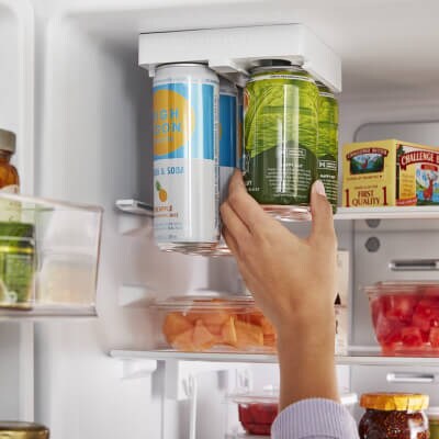 Person reaching for a canned beverage inside a refrigerator