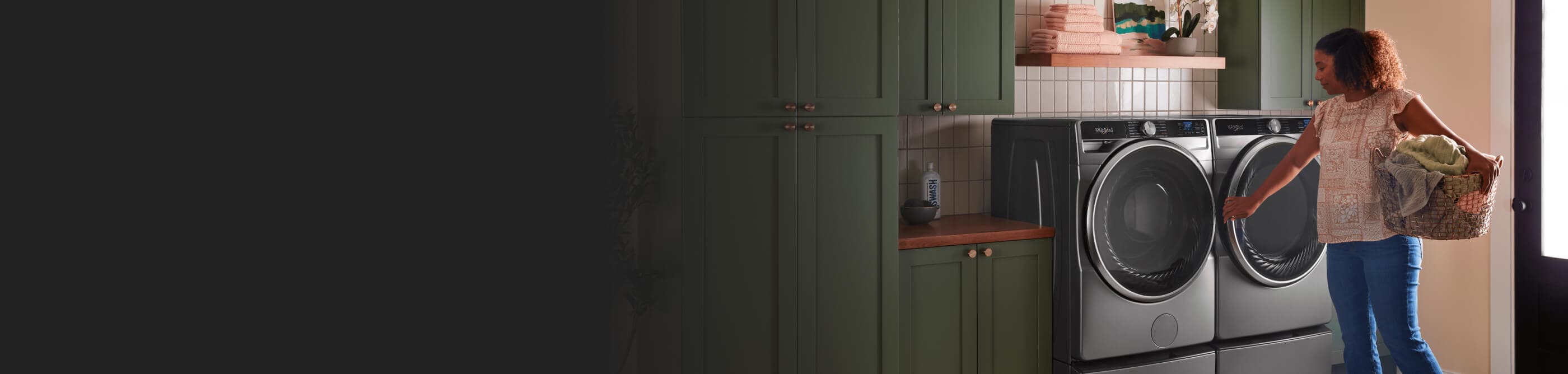 Person holding a laundry basket in front of a front load washer and dryer set