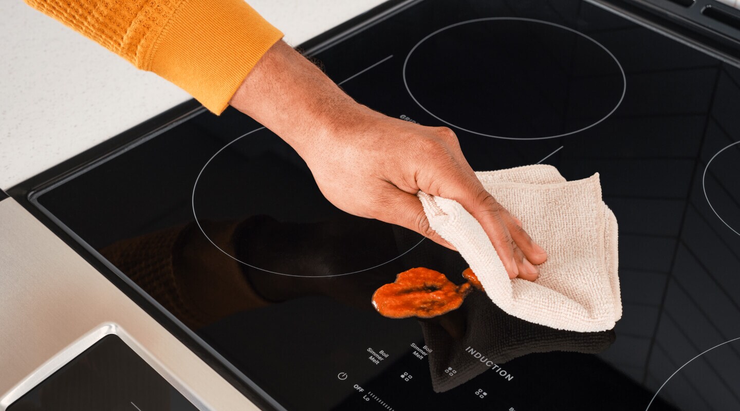 A person cleaning up a spill on an induction cooktop