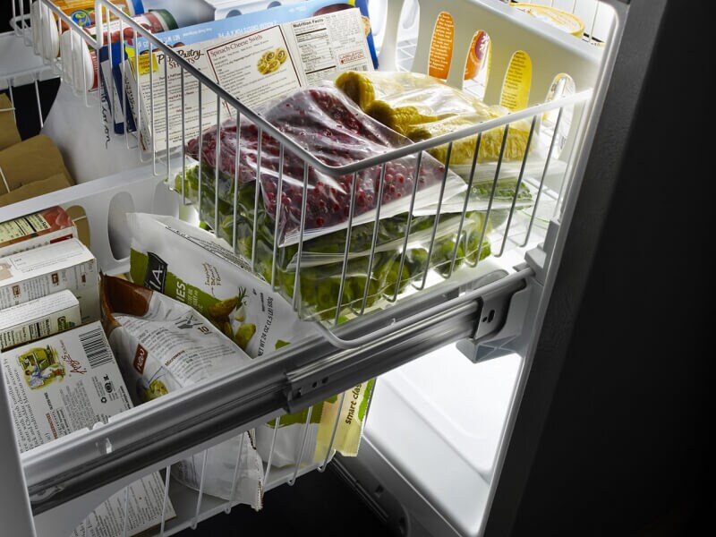 A tiered freezer drawer pulled out on a bottom-freezer refrigerator