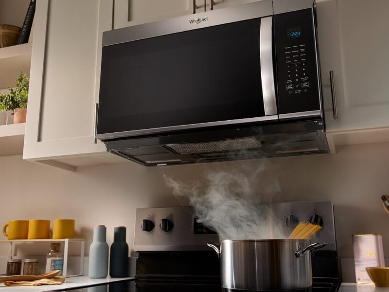 A Whirlpool® Over-the-Range Microwave with food cooking below A Whirlpool® Over-the-Range Microwave with food cooking below