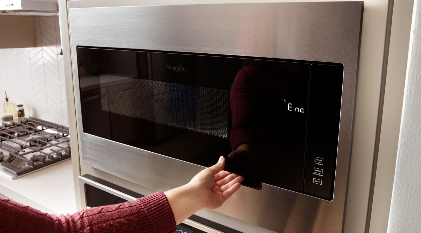 Person opening a Whirlpool® microwave Person opening a Whirlpool® microwave