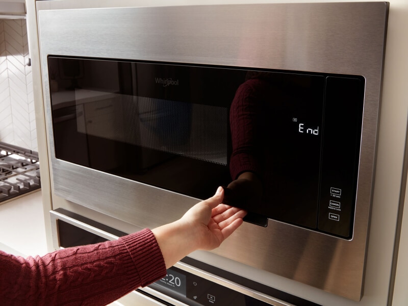 Person opening a Whirlpool® microwave Person opening a Whirlpool® microwave