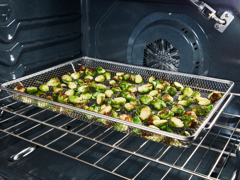 Vegetables in an air fryer basket in an oven Vegetables in an air fryer basket in an oven