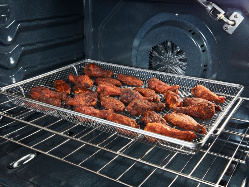 Chicken wings in an air fryer basket Chicken wings in an air fryer basket