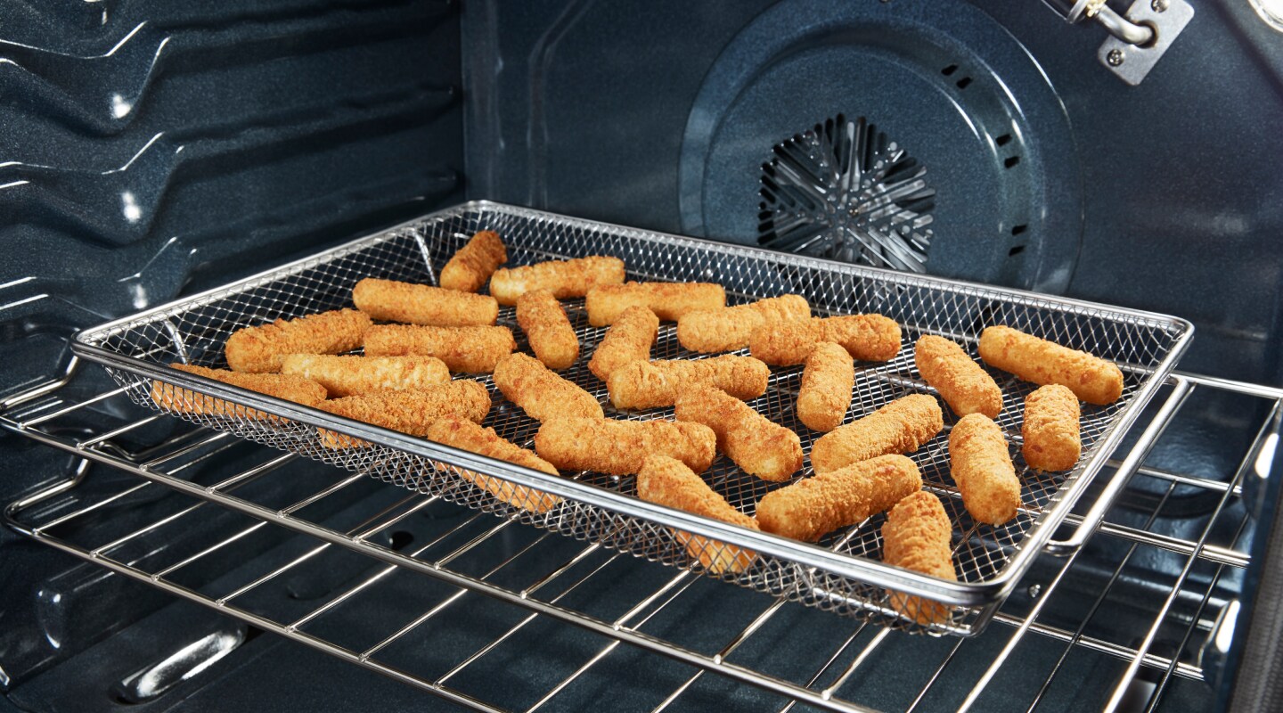 Mozzarella sticks in an air fryer basket in the oven