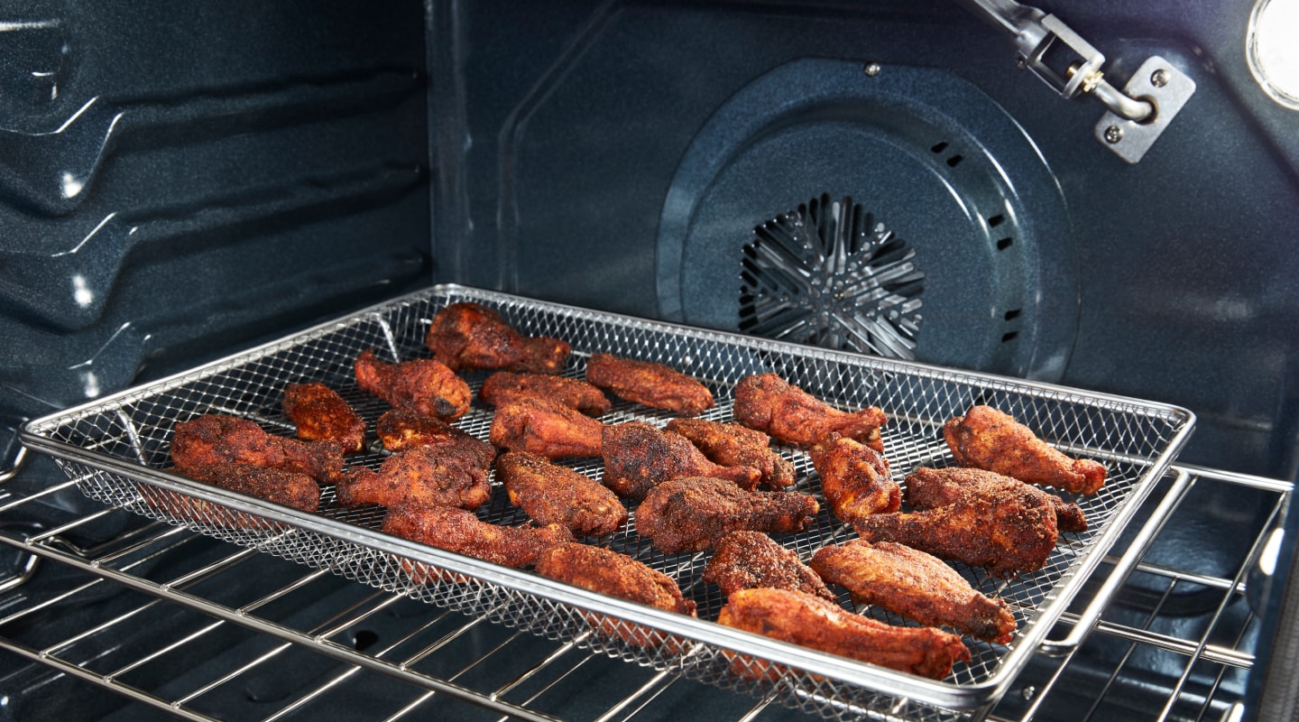 Chicken wings in an air fryer basket Chicken wings in an air fryer basket