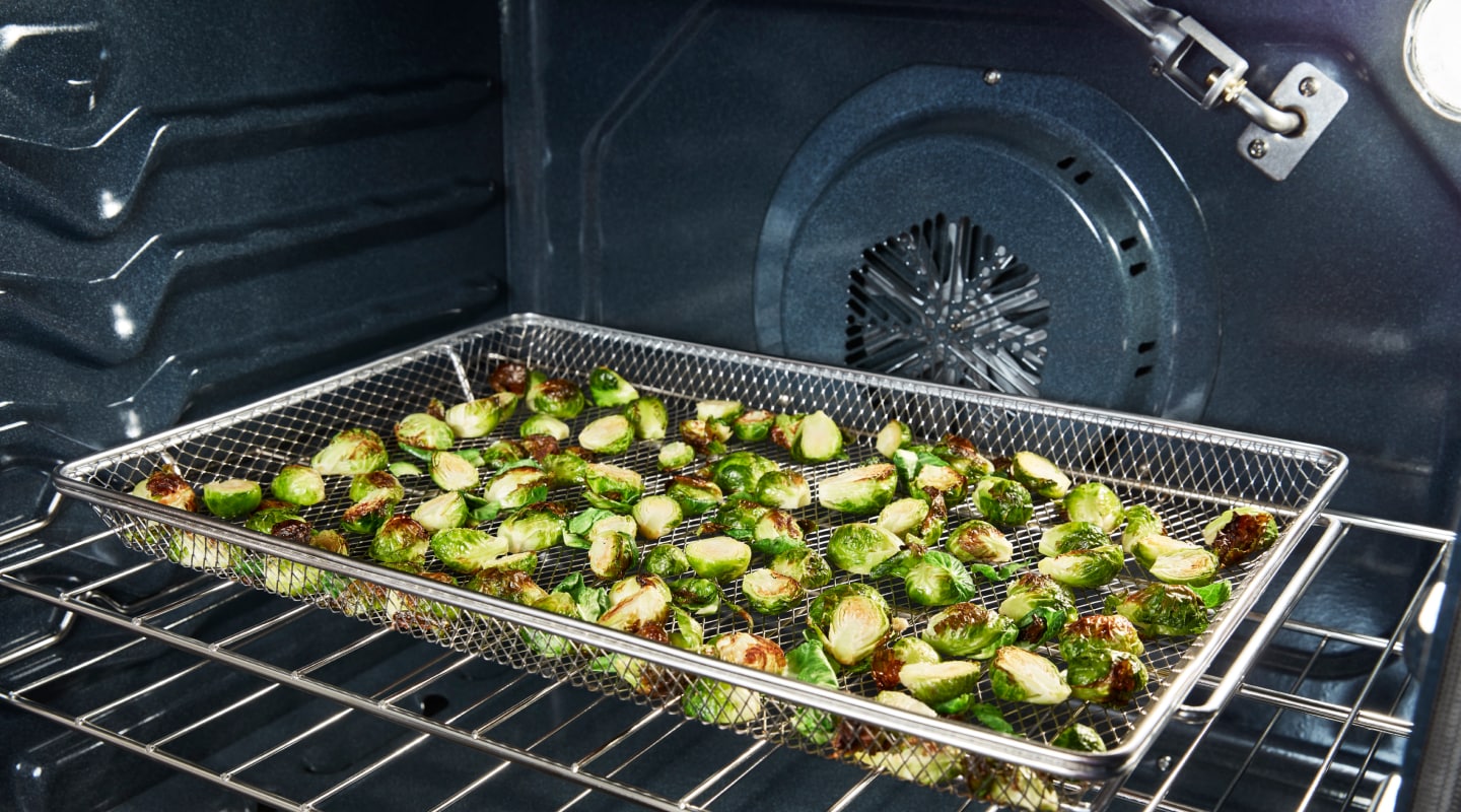 Vegetables in an air fryer basket in an oven Vegetables in an air fryer basket in an oven
