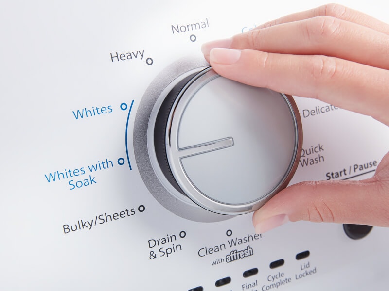 A person adjusting the settings of a washer A person adjusting the settings of a washer