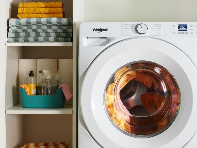 A laundry supply cabinet next to a white washer A laundry supply cabinet next to a white washer