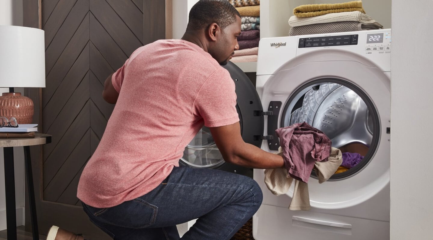 A person putting clothes into a Whirlpool® Washer