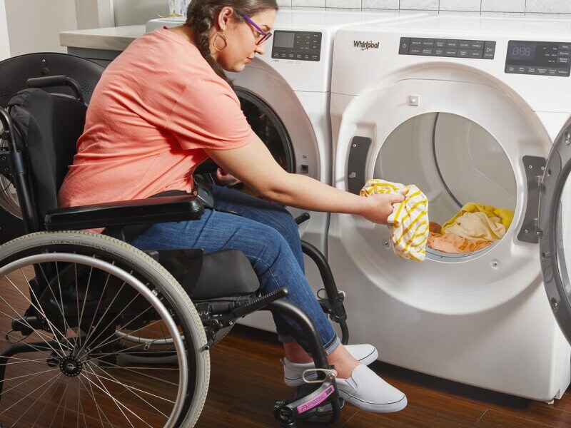 A person in a wheelchair putting clothes into a Whirlpool® Dryer A person in a wheelchair putting clothes into a Whirlpool® Dryer
