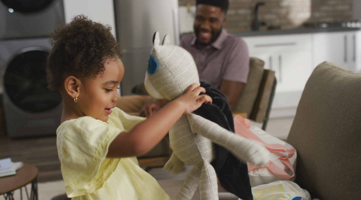 A child in a yellow dress playing with a stuffed animal A child in a yellow dress playing with a stuffed animal