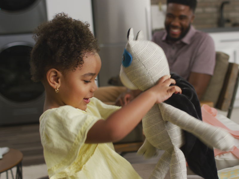 A child in a yellow dress playing with a stuffed animal A child in a yellow dress playing with a stuffed animal
