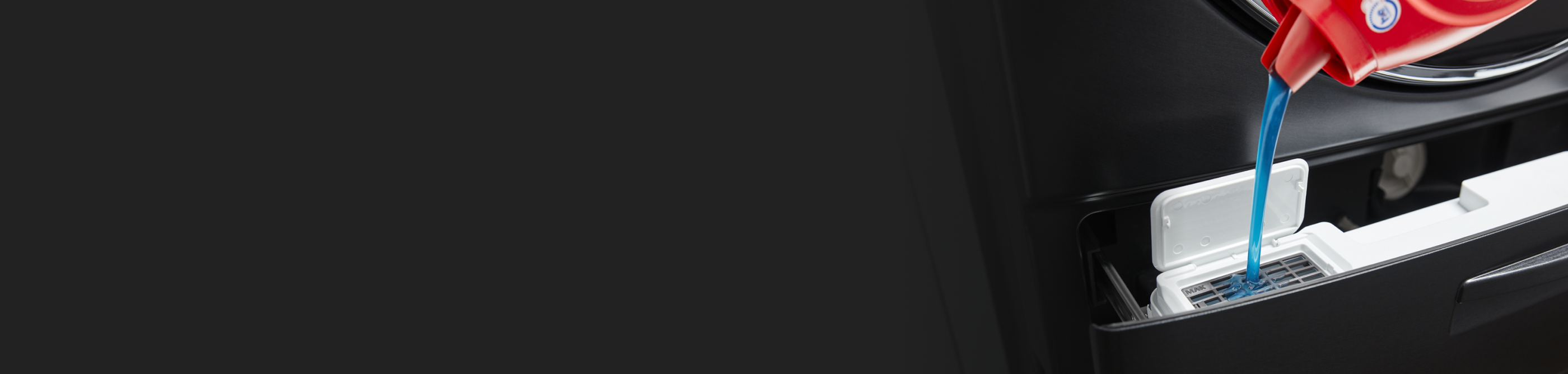 Closeup of blue liquid laundry detergent being poured into a washer detergent dispenser